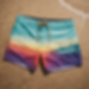 Colorful board shorts laid out on a sandy beach with ocean waves in the background